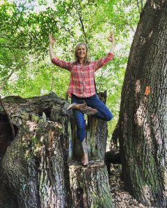 Blonde woman strikes yoga pose while standing on tree stump